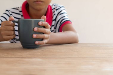 Asyalı çocuk elinde bir süt bardağı tutuyor..