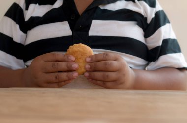 Asyalı çocuk elinde ekmek turtası tutuyor..