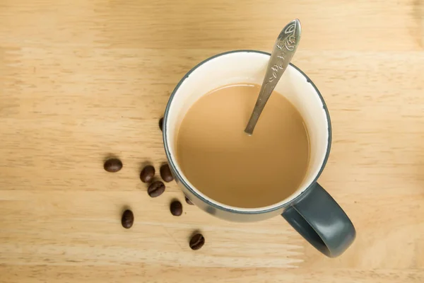 Una taza de café con leche y granos de café en la mesa — Foto de Stock