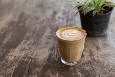 Ahşap masadaki bir bardak Latte sanat kahvesini kapat..