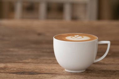 Pikolo Latte sanatı bir fincanın içinde Tahta masadaki sütten yapılmış güzel kalp sanatı.