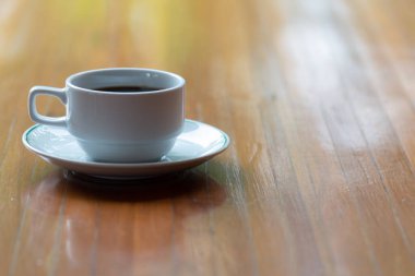 Bir fincan sıcak kahveyi ahşap masaya koy..