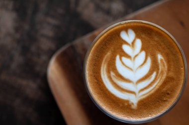 Ahşap masada bir bardak Latte sanat kahvesi..