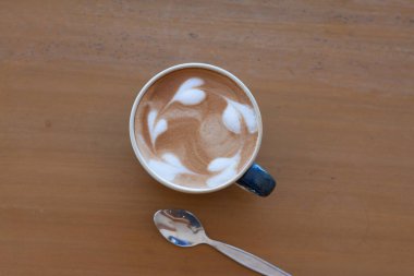 Bir fincan sıcak sütlü kahveyi ahşap masaya koy..