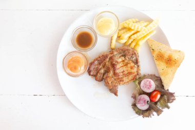 Pork pirzolası, beyaz tabak ve eski ahşap masa manzarası düzdü..