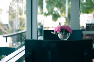 aşk arkaplanı ya da eski sevgililer günü arkaplanı için kopyalama alanı olan cam masadaki yapay pembe çiçek, pastel renk tonuna filtrelenmiş.