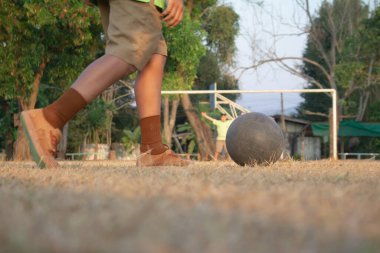 Spor sahasında futbol topu tekmeleyen bir çocuk. Çocuklar için futbol antrenmanı.