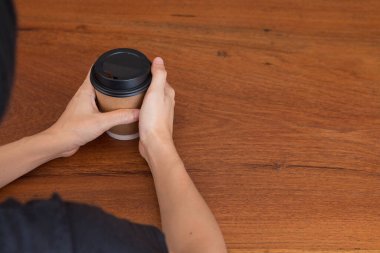 Bir kadın öğle vakti kahve dükkanında kahve fincanı tutuyor..