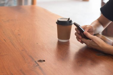 Cep telefonu kullanan bir kadının elleri kahve dükkanında kahve içiyor, internetten alışveriş yapıyor..