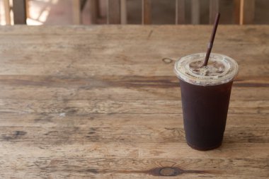 Americano kahvesi, kahve dükkanındaki ahşap masanın üzerinde paket plastik bardakta..