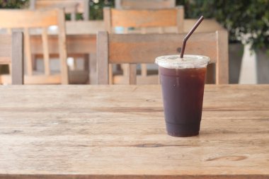 Americano kahvesi, kahve dükkanındaki ahşap masanın üzerinde paket plastik bardakta..