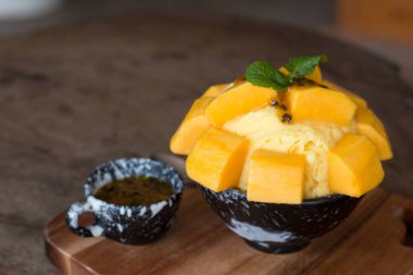 Mango dondurması ve çarkıfelek meyvesi seramik kasede en sevilen yaz tatlısı olarak ahşap masa üstünde yeniliyor..