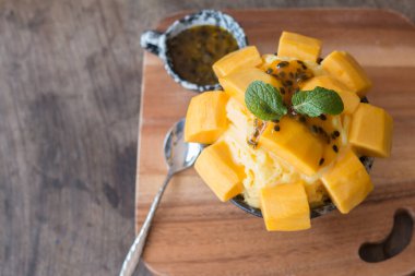 Mango dondurması ve çarkıfelek meyvesi seramik kasede en sevilen yaz tatlısı olarak ahşap masa üstünde yeniliyor..