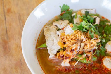 Baharatlı erişte çorbası, domuz eti, sebze ve ahşap masada servis edilen domuz eti..