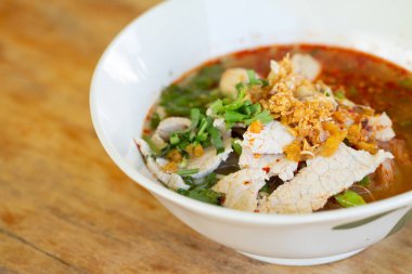 Baharatlı erişte çorbası, domuz eti, sebze ve ahşap masada servis edilen domuz eti..