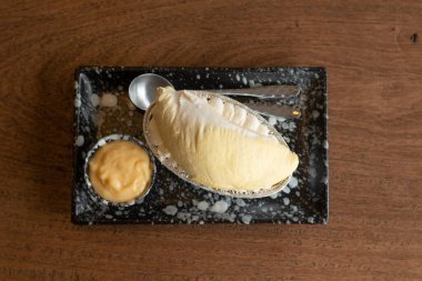 Üzerinde Durian meyvesi ve ahşap masa arkasında Durian kreması olan cheesecake..