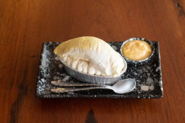 Üzerinde Durian meyvesi ve ahşap masa arkasında Durian kreması olan cheesecake..