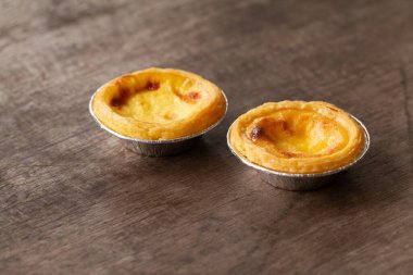 Alüminyum folyo bardakta yumurtalı turtalar ahşap masada, geleneksel Portekiz tatlıları kahve dükkanında servis edilir..