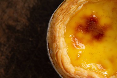 Alüminyum folyo bardakta yumurtalı turtalar ahşap masada, geleneksel Portekiz tatlıları kahve dükkanında servis edilir..