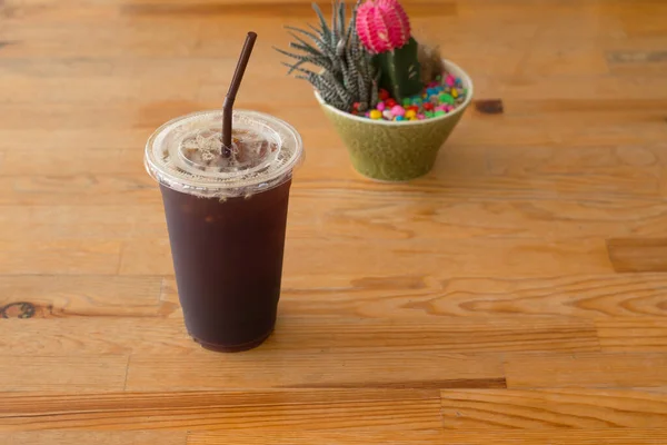 Americano iced coffee in takeaway plastic cup on wooden desk in coffee's shop.