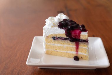 Beyaz tabakta böğürtlenli pasta dilimleri.