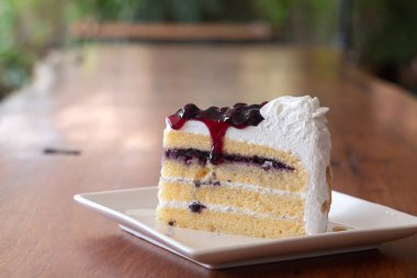 Beyaz tabakta böğürtlenli pasta dilimleri.