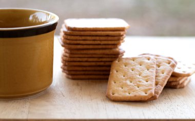 Tahta masada sıcak kahveyle servis edilen sütlü kraker, mola..