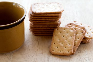 Tahta masada sıcak kahveyle servis edilen sütlü kraker, mola..