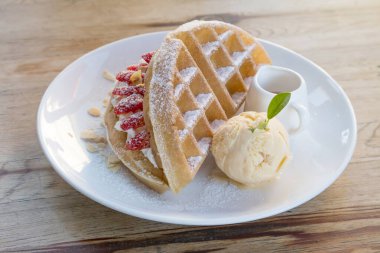 Vanilyalı dondurmayı waffle ve ahşap masa arkasında taze çilekle kapat..