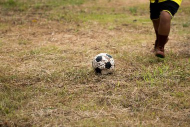 Genç Asyalı çocuk kırsalda futbol oynuyor..