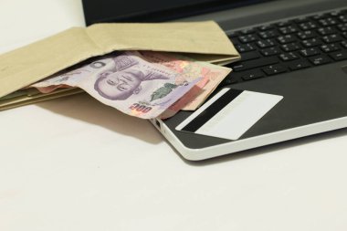 İnternetten alışveriş yaptıktan sonra kredi kartı, Tayland 500 Baht para birimi ve dizüstü bilgisayar, E-ticaret ağı pazarlama kavramı bulanıklığı.