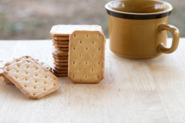 Tahta masada sıcak kahveyle servis edilen sütlü kraker, mola..