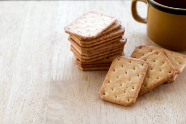 Tahta masada sıcak kahveyle servis edilen sütlü kraker, mola..