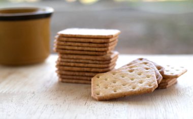 Tahta masada sıcak kahveyle servis edilen sütlü kraker, mola..