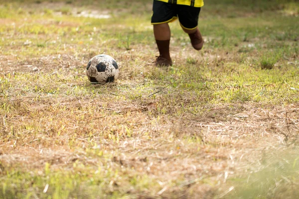 Genç Asyalı çocuk kırsalda futbol oynuyor..