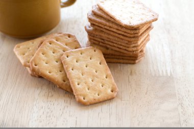 Tahta masada sıcak kahveyle servis edilen sütlü kraker, mola..