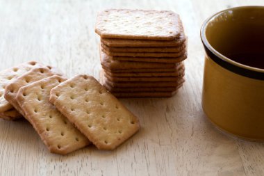 Tahta masada sıcak kahveyle servis edilen sütlü kraker, mola..
