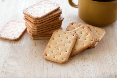 Tahta masada sıcak kahveyle servis edilen sütlü kraker, mola..