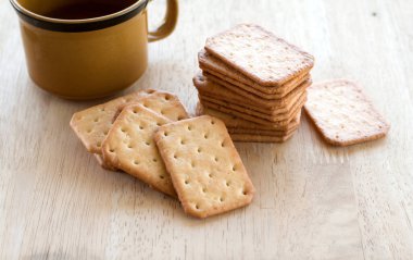Tahta masada sıcak kahveyle servis edilen sütlü kraker, mola..