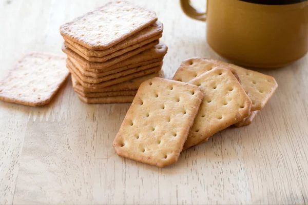 Tahta masada sıcak kahveyle servis edilen sütlü kraker, mola..
