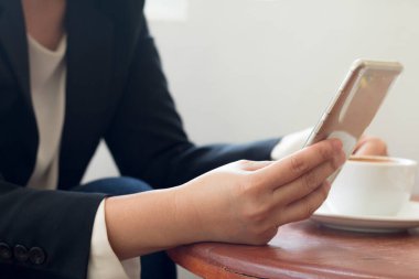 Bir iş kadını elinde akıllı bir telefon tutuyor, internette çalışıyor ya da cep telefonundan son haberleri kontrol ediyor..