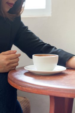 Bir iş kadını, iş sırasında elinde beyaz bir kahve fincanı tutuyor..