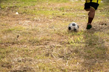 Genç Asyalı çocuk kırsalda futbol oynuyor..