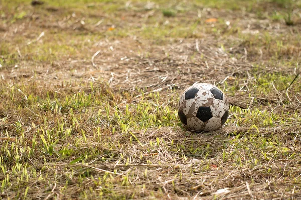 Eski futbol topu çimlerin üzerinde, kötü futbol sahası kırsalda.