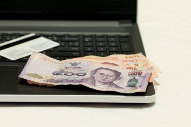 İnternetten alışveriş yaptıktan sonra kredi kartı, Tayland 500 Baht para birimi ve dizüstü bilgisayar, E-ticaret ağı pazarlama kavramı bulanıklığı.