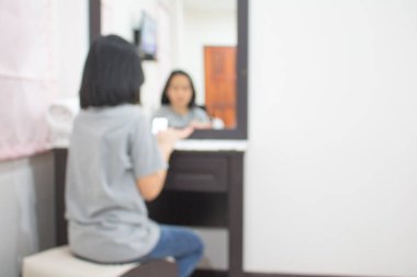 Yong kızının bulanıklığı bir tuvalet masasının önünde giyiniyor..