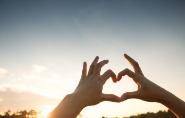 Eller kalp şeklinde aşk, siluet gibi eller güneş batarken kalp şekli oluşturur..
