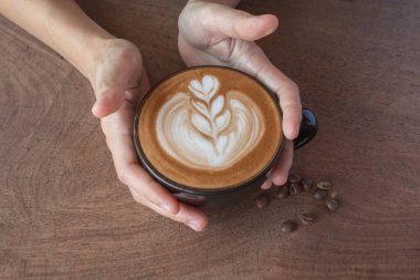 Tahta masadaki bir fincan sıcak latte sanat kahvesi..