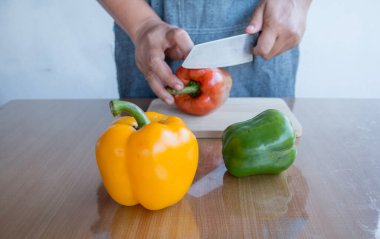 Mutfak masasında ahşap kesme tahtasının üzerinde pişmiş taze renkli dolmalık biber pişirmeye hazır..