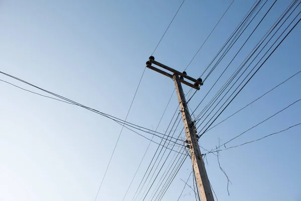 Power pole with power lines on blue sky background.